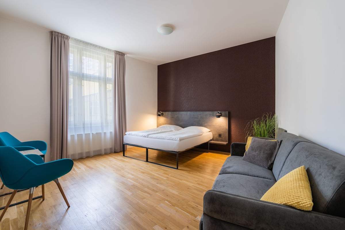 Une chambre à coucher moderne avec un lit, un canapé et un fauteuil.