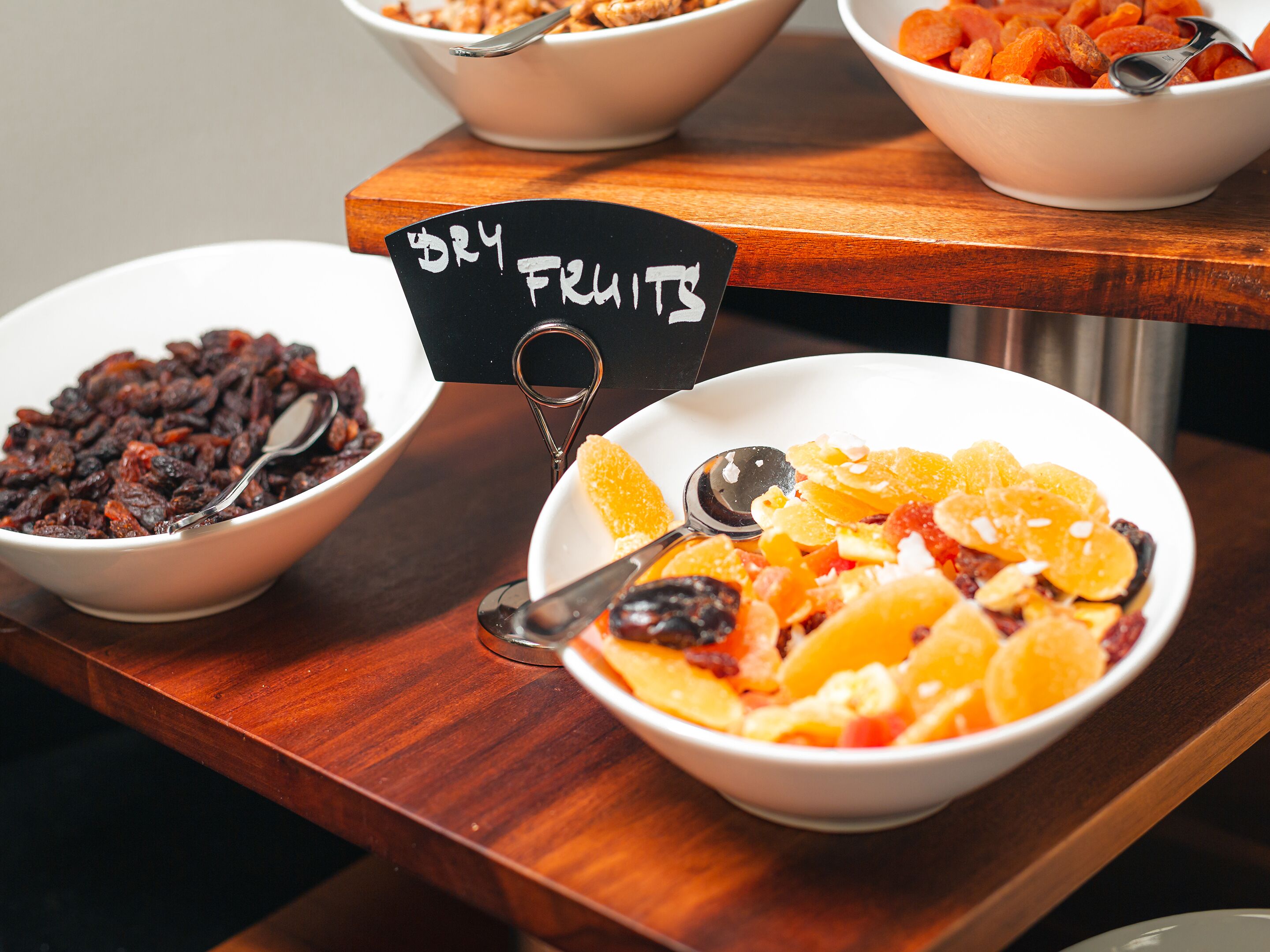 Un buffet avec des bols remplis de fruits secs et un panneau indiquant la section.