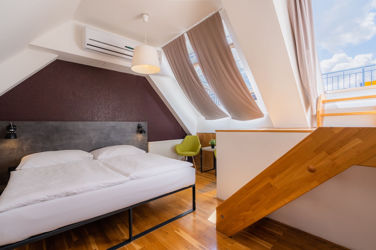 Une chambre à coucher moderne, avec un lit, un bureau, une chaise et une vue sur le ciel par la fenêtre.