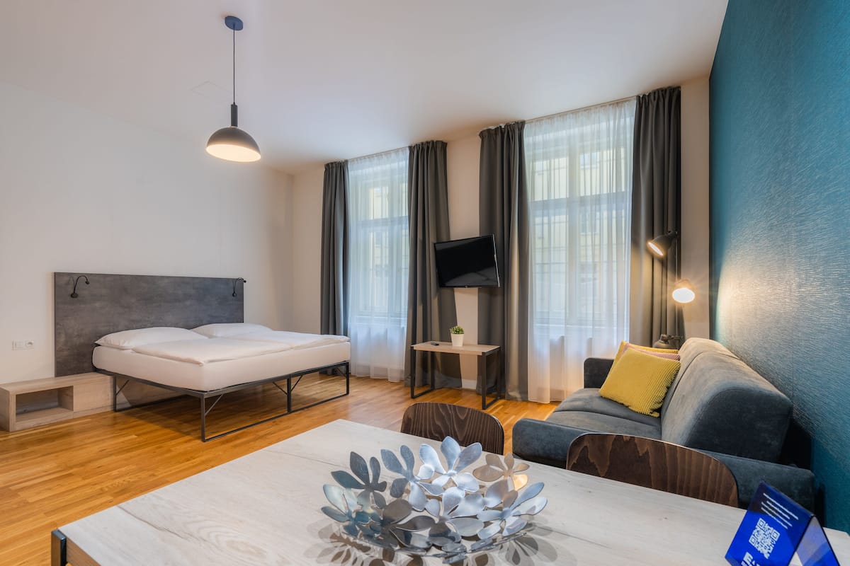 Une chambre d’hôtel moderne équipée d’un lit, d’un canapé, d’une télévision et d’une table agrémentée d’un vase décoratif.