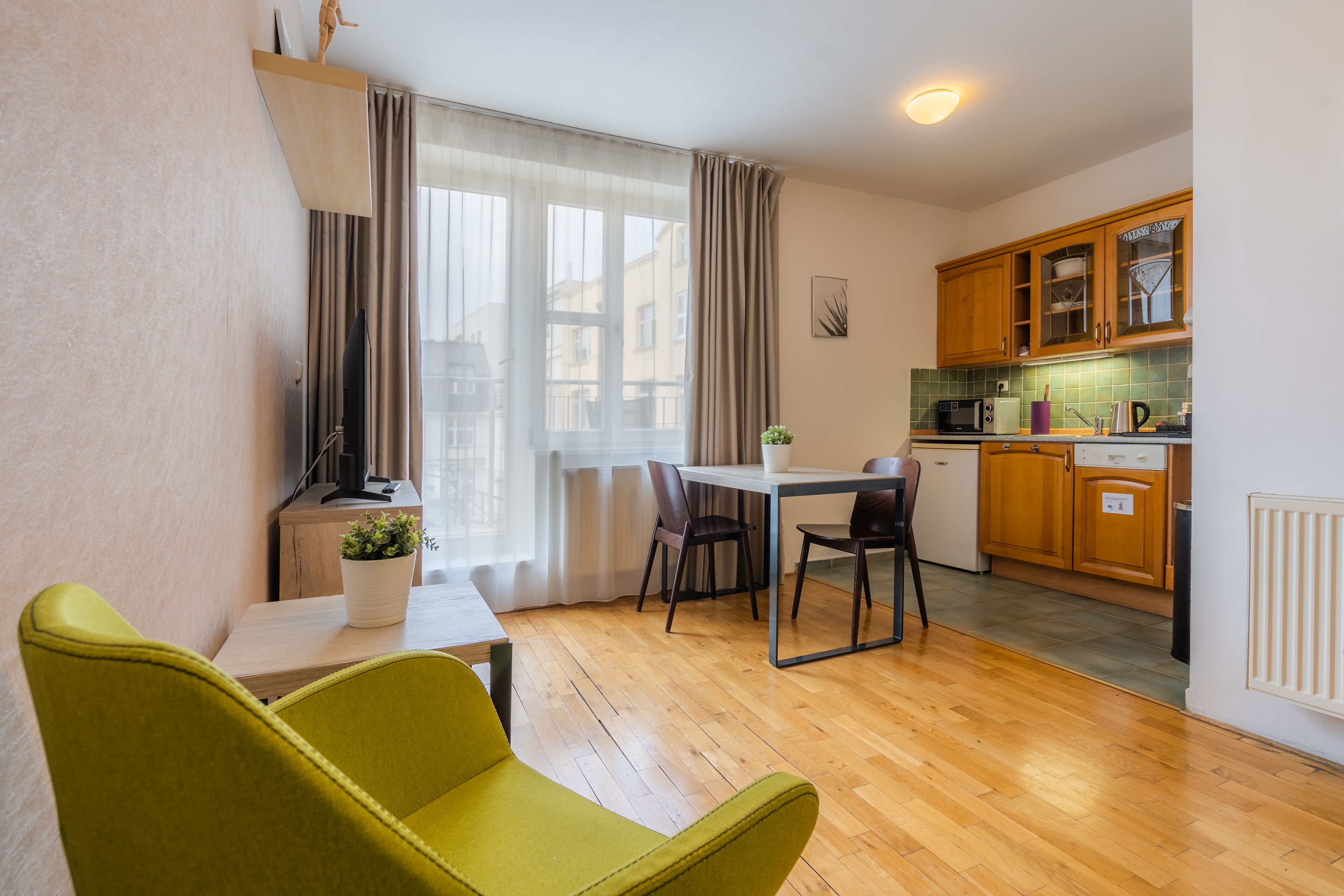 A compact living space with a dining area, a kitchenette, and a window with curtains.