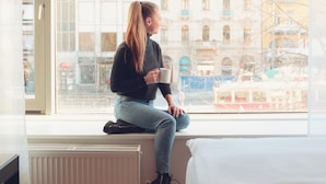 A person sitting by a window with a view of a cityscape.