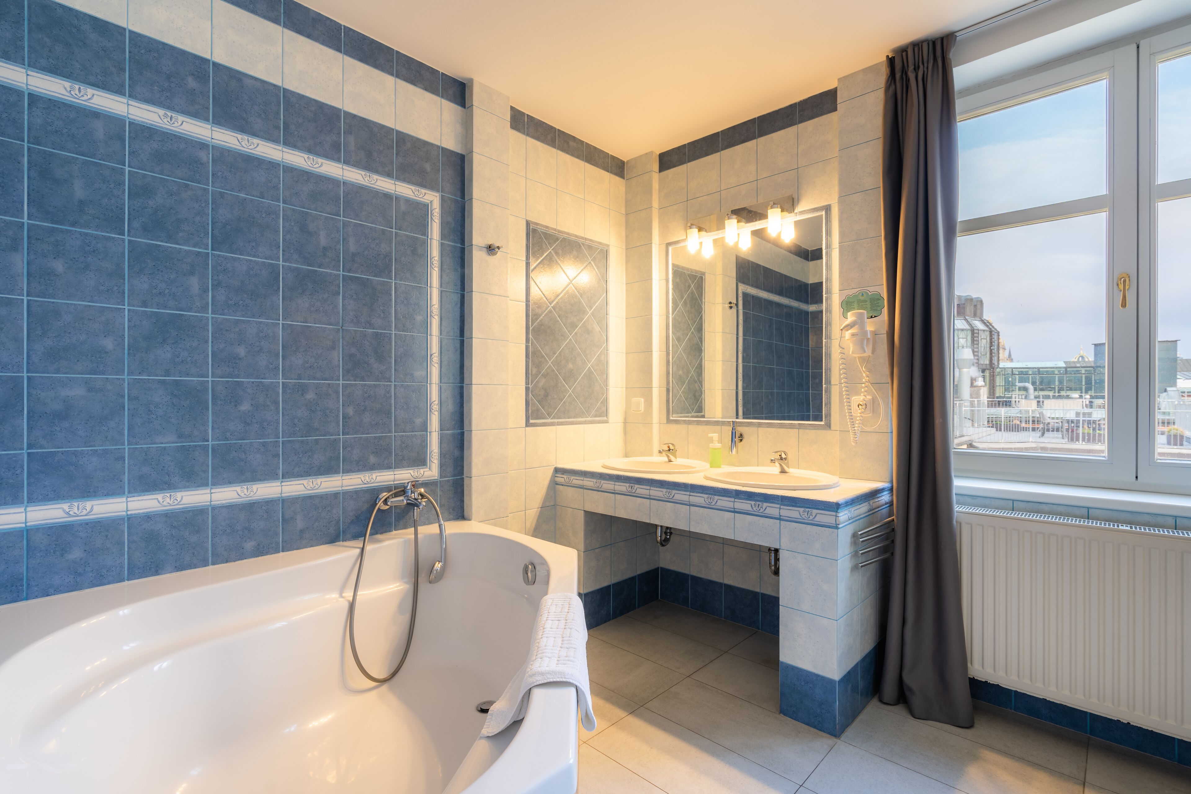 Un baño moderno con una bañera, dos lavamanos y un espejo grande.