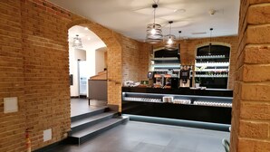 A modern bar area with brick walls, a counter with glassware, and a staircase leading to another level.