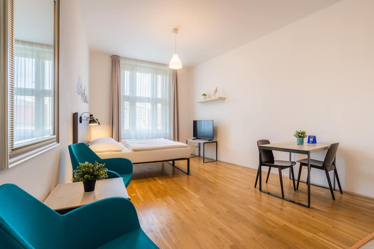 Une chambre d’hôtel moderne équipée d’un lit, d’un bureau avec une chaise, d’une télévision et d’une plante en pot.