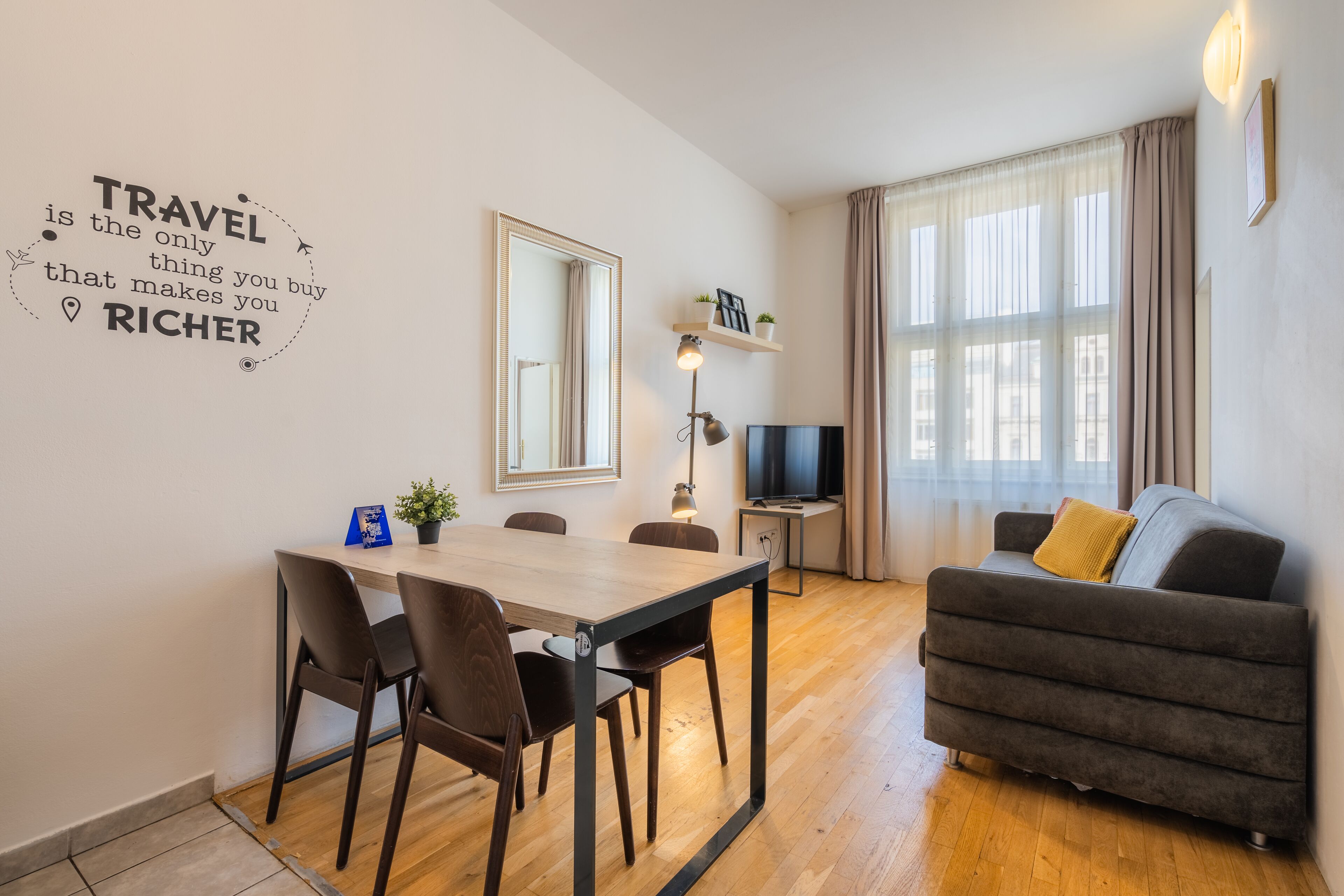 Una sala de estar moderna con comedor, sofá, televisor y una pared con una cita de viajes.