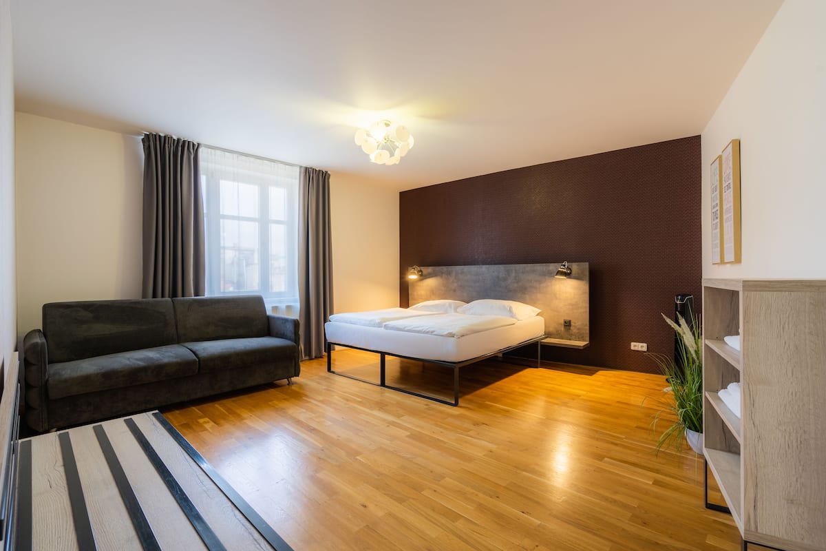 Une chambre à coucher moderne avec un lit, un canapé et un plancher en bois.