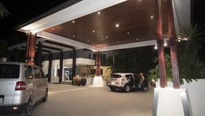 A modern building with a covered parking area, featuring a wooden ceiling and multiple light fixtures.