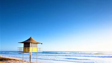 A lifeguard tower on a beach with clear skies and ocean waves.