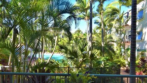 A tropical resort with a pool surrounded by palm trees and a view of the ocean.