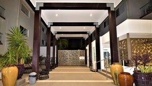 A hotel lobby with a central open space, potted plants, and a decorative gate.