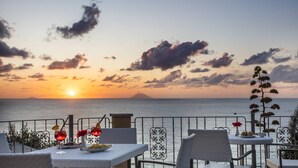 A seaside terrace with a table set for two, overlooking the ocean at sunset. - Tonicello Resort & SPA (Ricadi)
