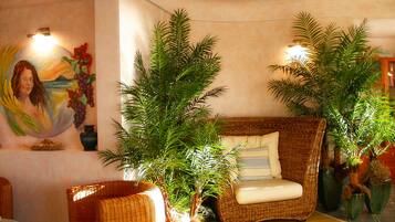 A room with a wicker sofa, a small table, and potted plants.