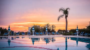 Una piscina al aire libre, sombrillas, sillones reclinables de piscina