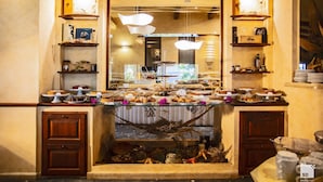 A buffet setup with various food items, wooden shelves, and a decorative fireplace. - Tonicello Resort & SPA (Ricadi)