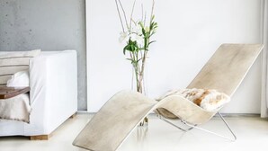 Een moderne woonkamer met een witte bank, een beige fauteuil en een vaas met witte bloemen.