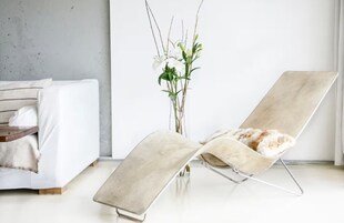 Ein modernes Wohnzimmer mit einem weißen Sofa, einem beigefarbenen Sessel und einer Vase mit weißen Blumen.