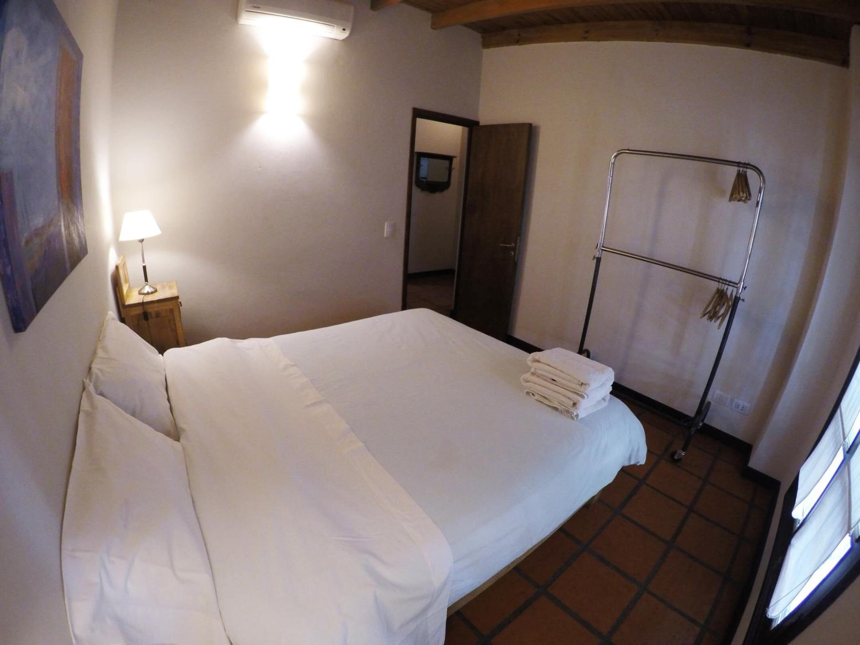 Ein Schlafzimmer mit einem großen Bett, einer Nachttischlampe, einem Handtuchhalter und einem Spiegel.