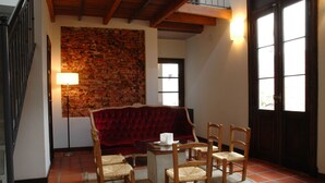 A cozy living room with a brick wall, a red velvet sofa, a glass coffee table, and wooden chairs. -  Posada Gotan (Buenos Aires)