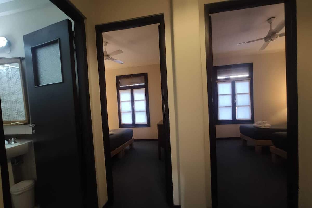 A hallway with two beds, a window, and a ceiling fan.