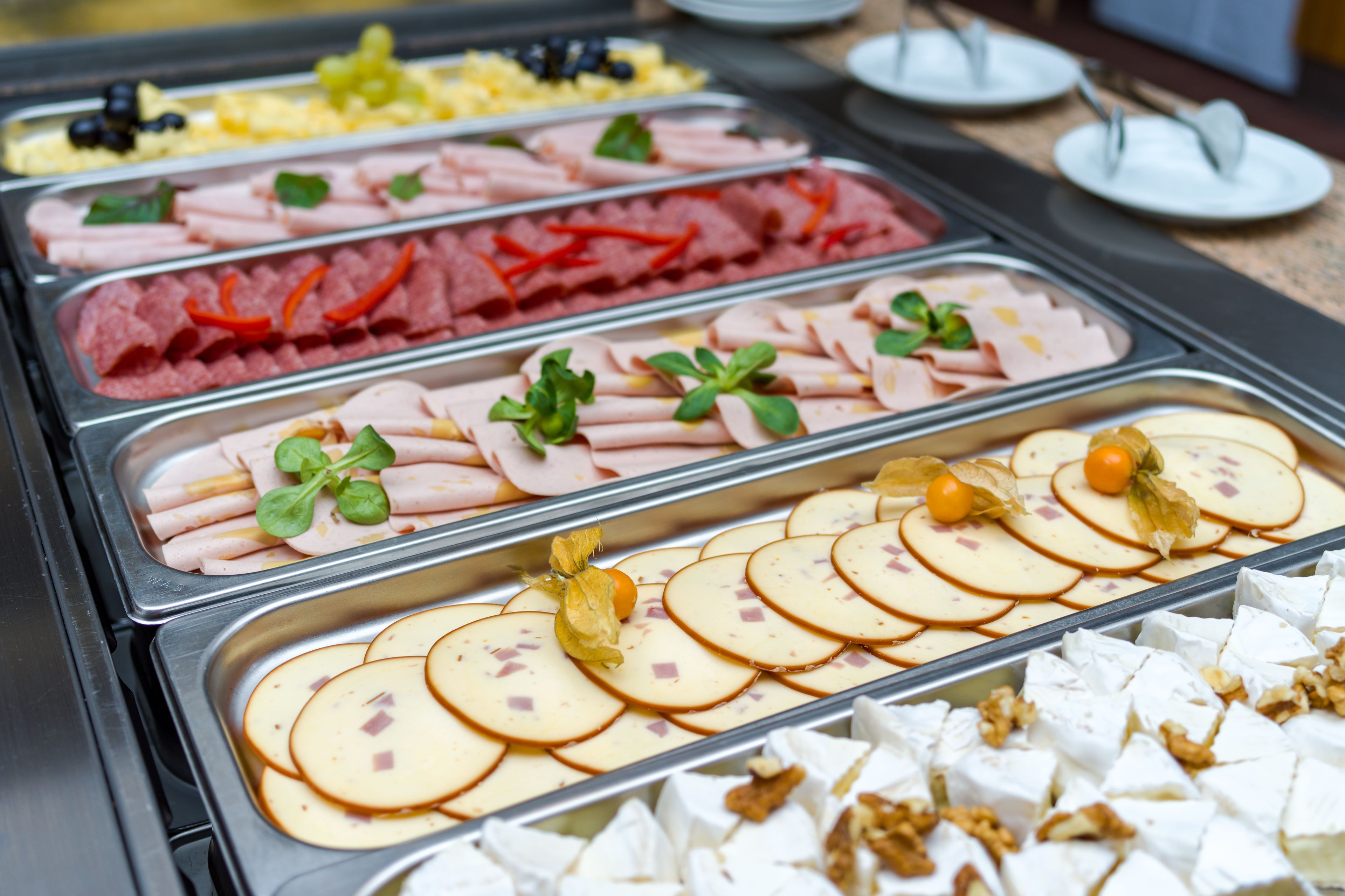 Buffet com diversas opções de comida, incluindo carnes, queijos e frutas.