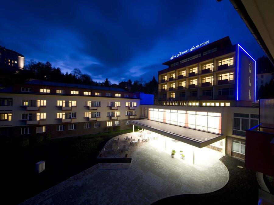 Un hôtel à étages, doté d’un espace extérieur aménagé pour les clients et d’une façade bien éclairée.