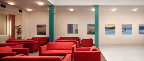 A modern lobby with red seating, artwork on the walls, and a skylight.