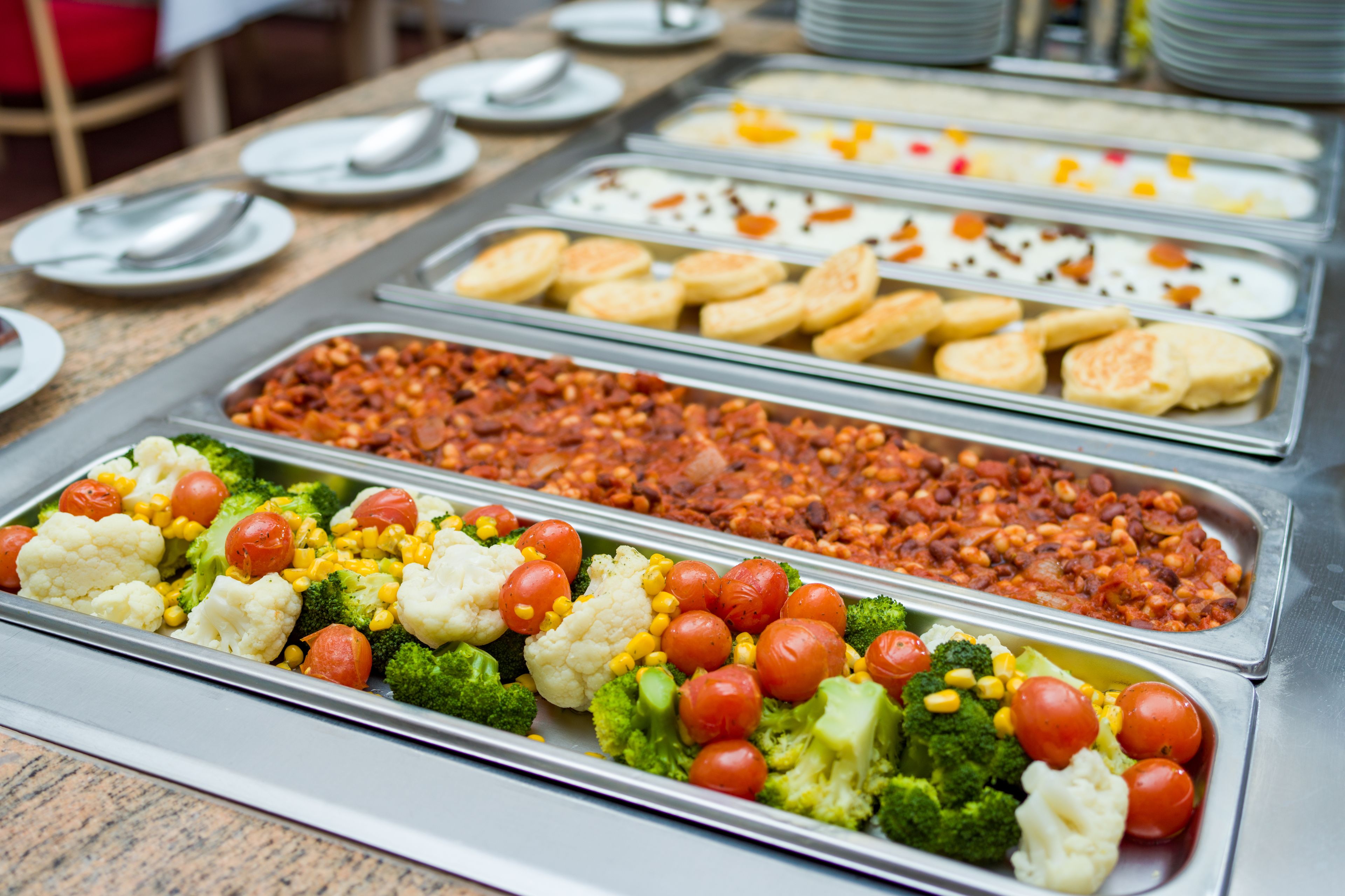 A buffet with various food options including vegetables, beans, and pastries.