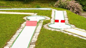 A golf course with a green, a red flag, and a white flag.