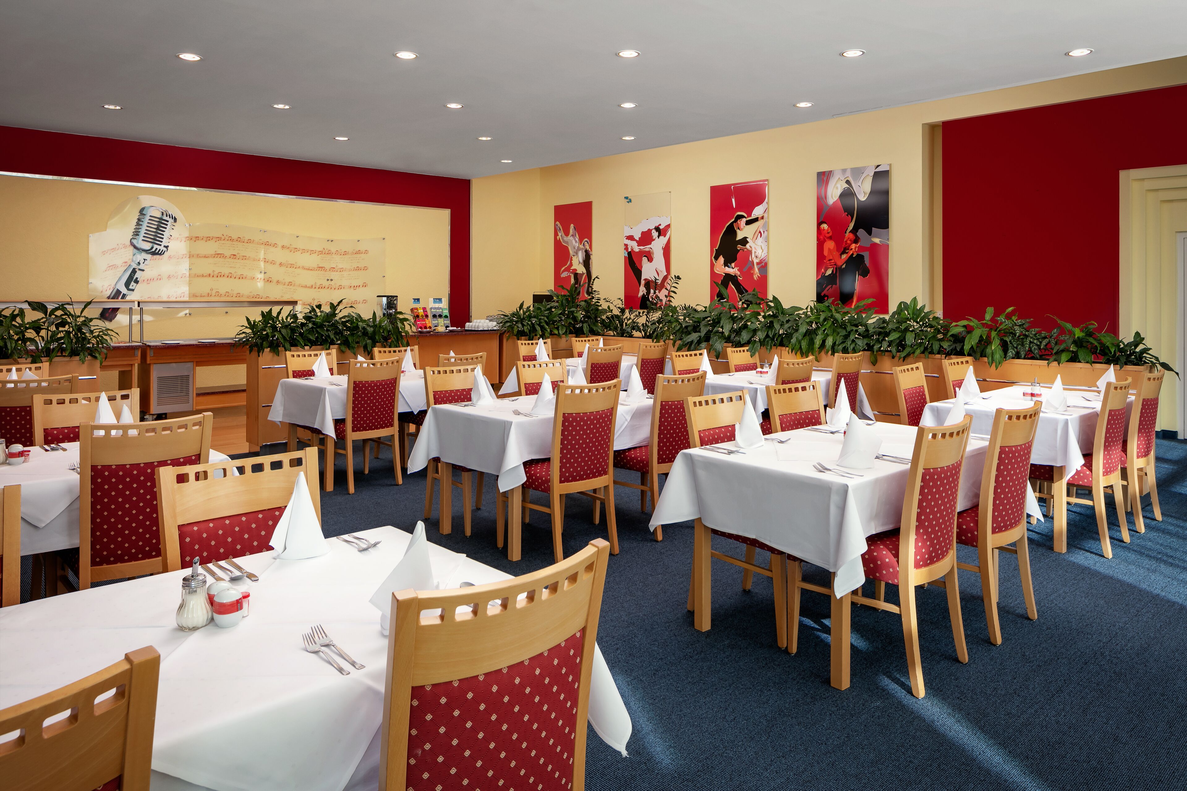 A conference room with multiple tables and chairs, white tablecloths, and red chairs.