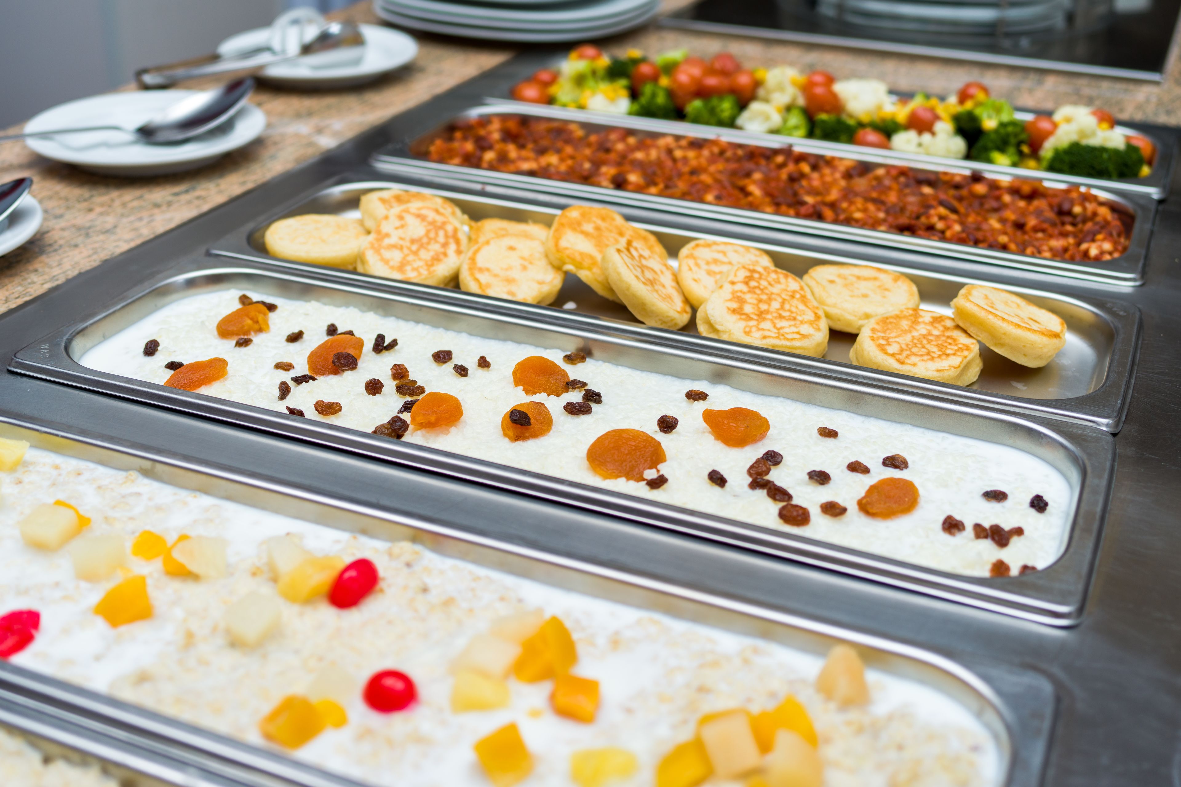 A buffet with various food options including rice, fruit, and pastries.