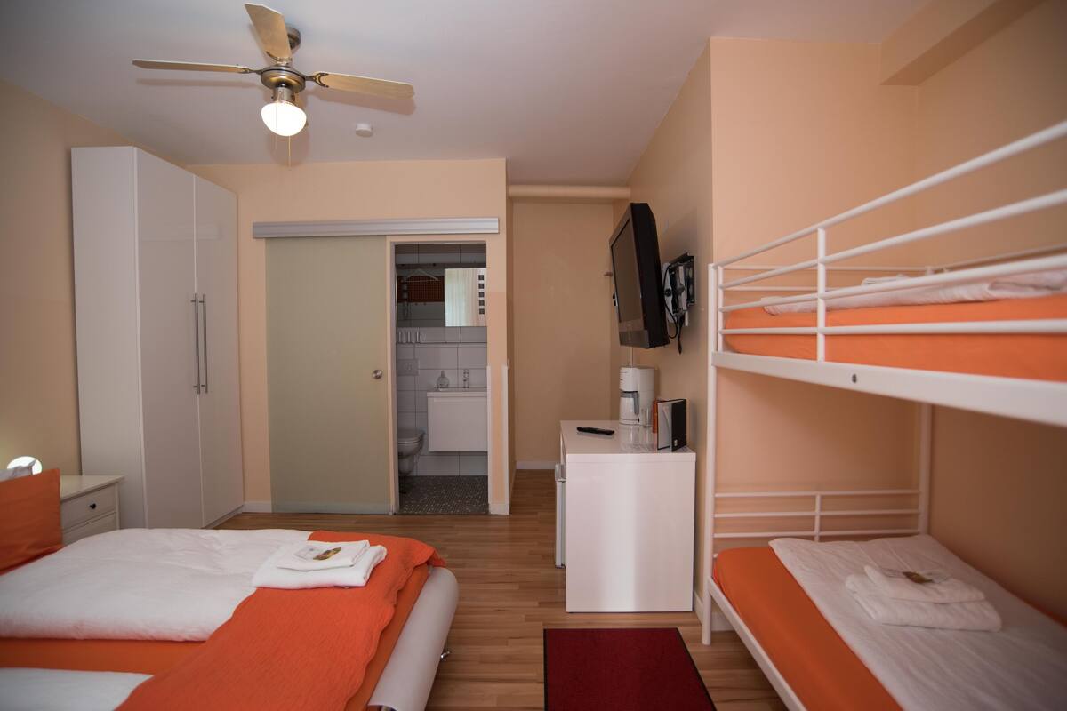 Un dormitorio con cama, escritorio, televisión y literas.