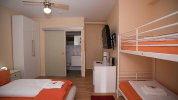 Ein Schlafzimmer mit einem Bett, einem Schreibtisch, einem Fernseher und einem Stockbett.