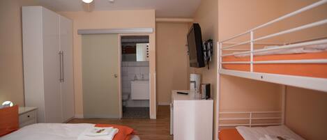 A bedroom with a bed, a desk, a TV, and a bunk bed.