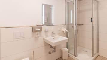 A modern bathroom with a glass-enclosed shower, a white sink, and a mirror above the sink.