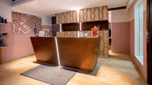 A reception area with a wooden reception desk, a map on the wall, and a patterned wall behind the desk. - Altstadthotel Grauer Wolf (Erlangen)