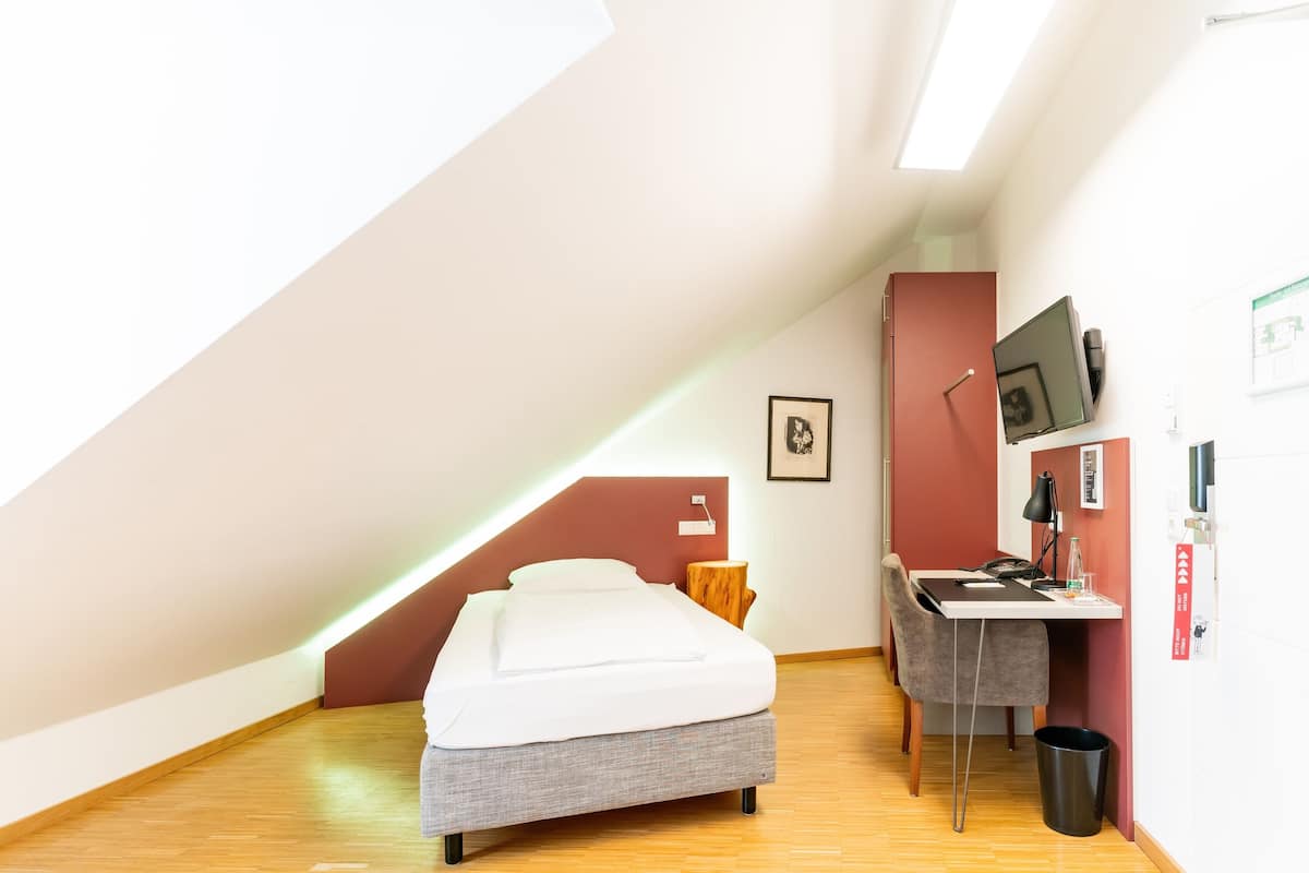 A small, modern room with a bed, desk, and chair.