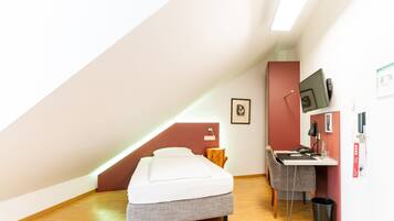A small, modern room with a bed, desk, and chair.