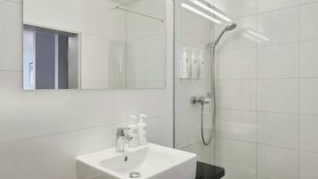 A modern bathroom with a white sink, mirror, and shower.