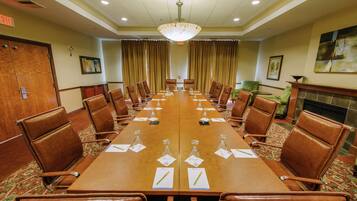 A conference room with a long table, brown leather chairs, and a chandelier.