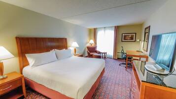 Une chambre d’hôtel avec un grand lit, un bureau avec un ordinateur, une chaise et un téléviseur.