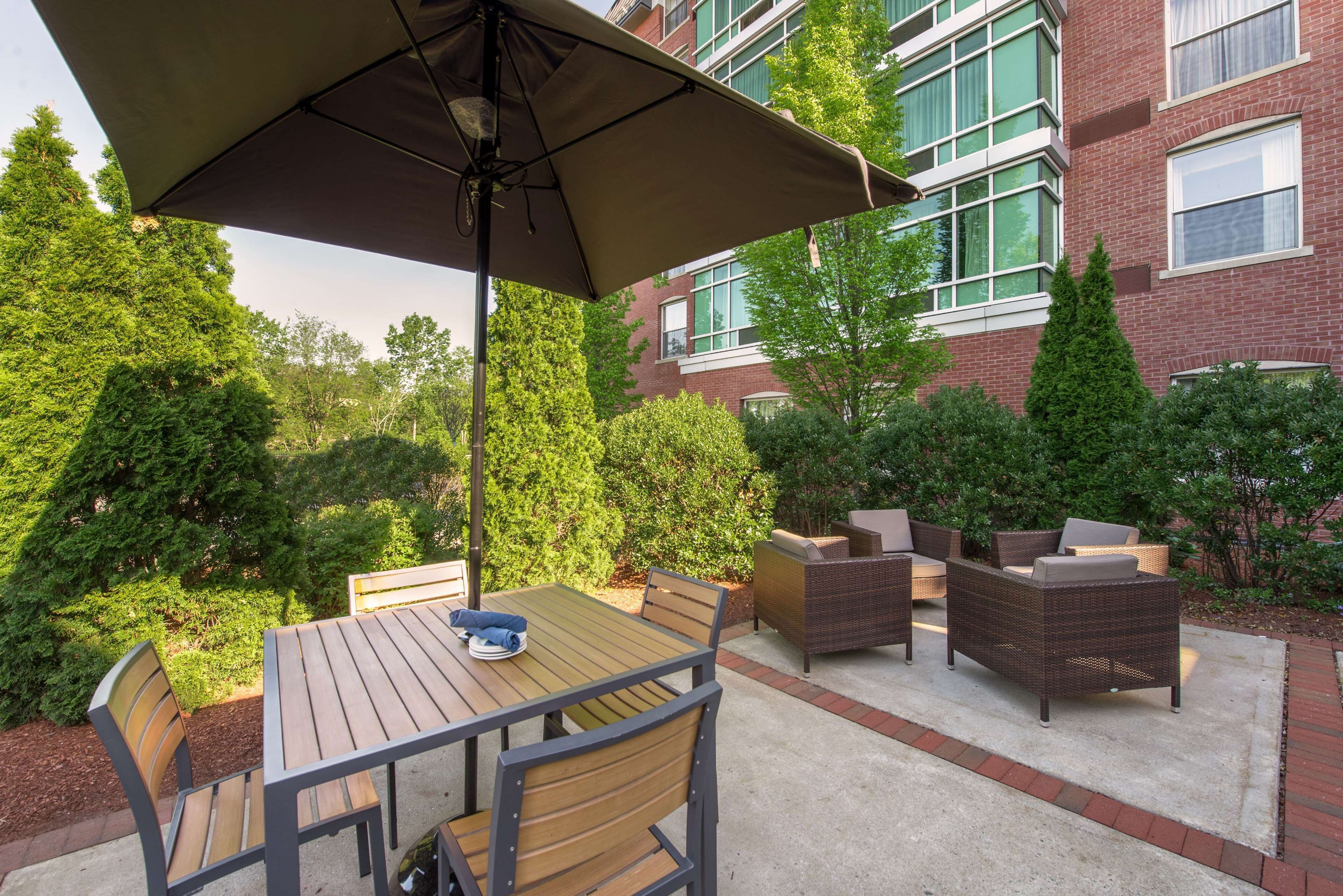 An outdoor patio with a table and chairs, a large umbrella, and wicker furniture.