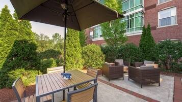 An outdoor patio with a table and chairs, a large umbrella, and wicker furniture.