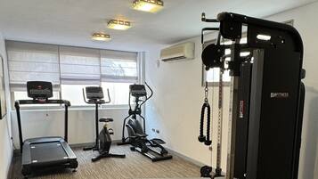 A gym with treadmills, elliptical machines, a bench press, and a cable machine.