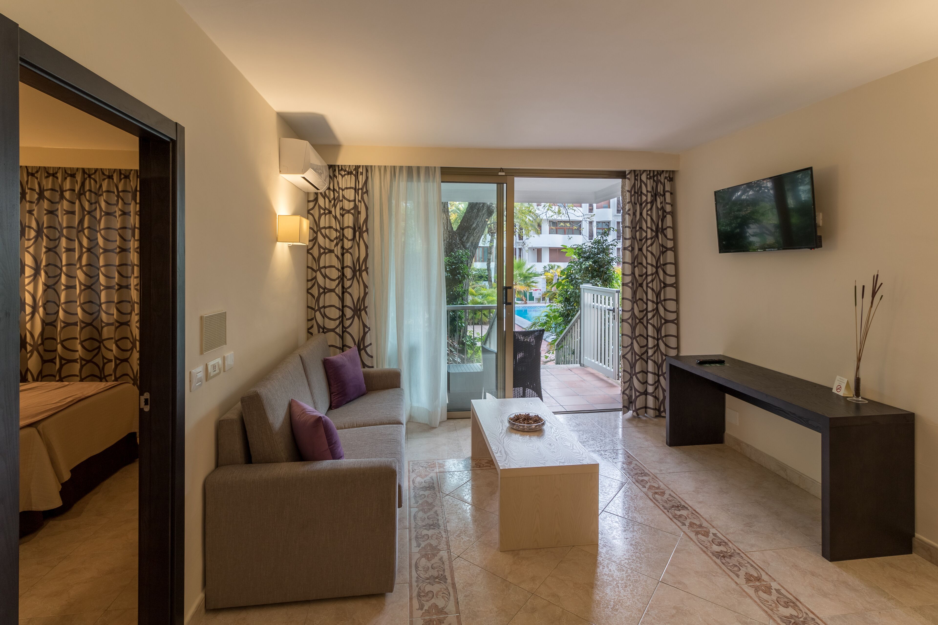 A modern living room with a sofa, coffee table, and a flat-screen TV mounted on the wall.