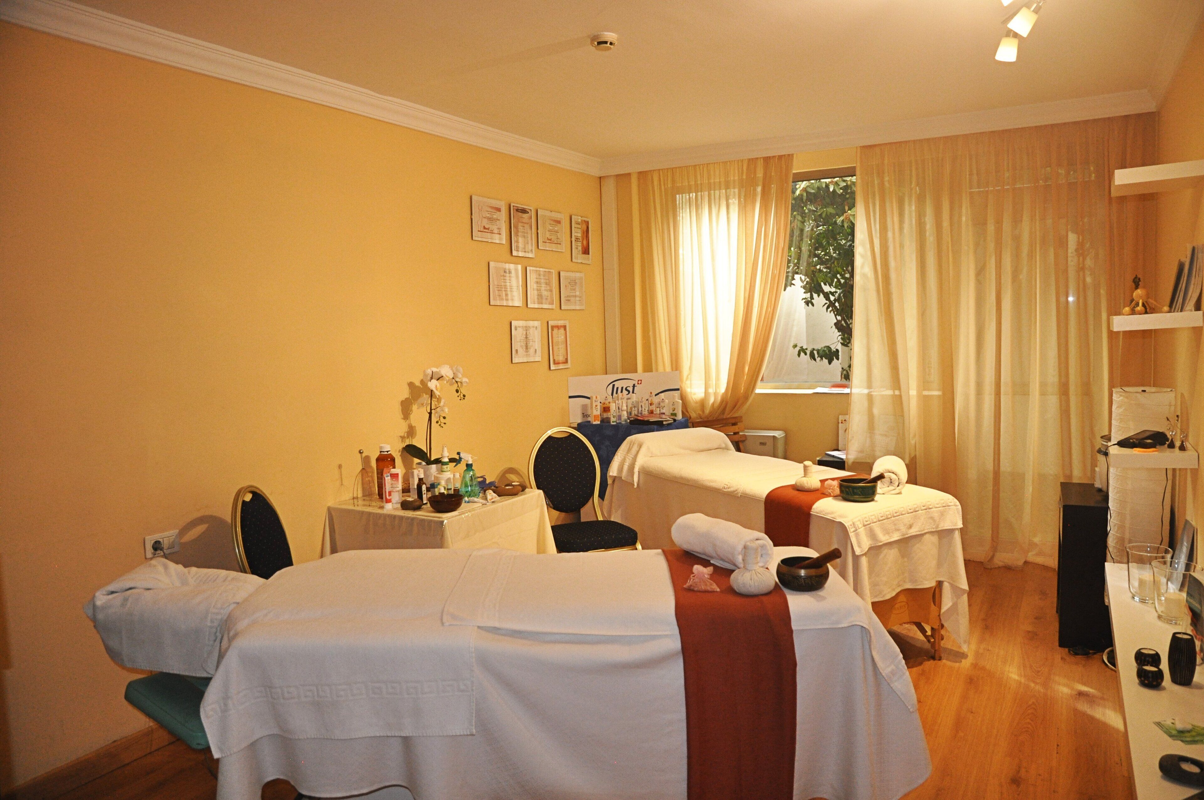 Une chambre d’hôtel avec deux lits, une petite table avec des articles de toilette, une chaise et une fenêtre avec des rideaux.