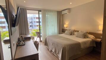 Une chambre d’hôtel équipée d’un lit, d’un bureau, d’une chaise et d’un téléviseur fixé au mur.
