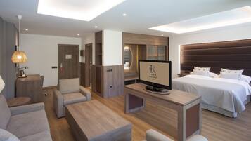 Ein modernes Hotelzimmer mit einem großen Bett, einem Fernseher, einer Couch und einem Schreibtisch.