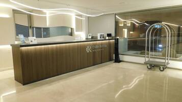A hotel reception desk with a wooden finish and a glass partition.