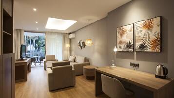 A modern hotel room with a wooden desk, comfortable seating, a flat-screen TV, and artwork on the walls.